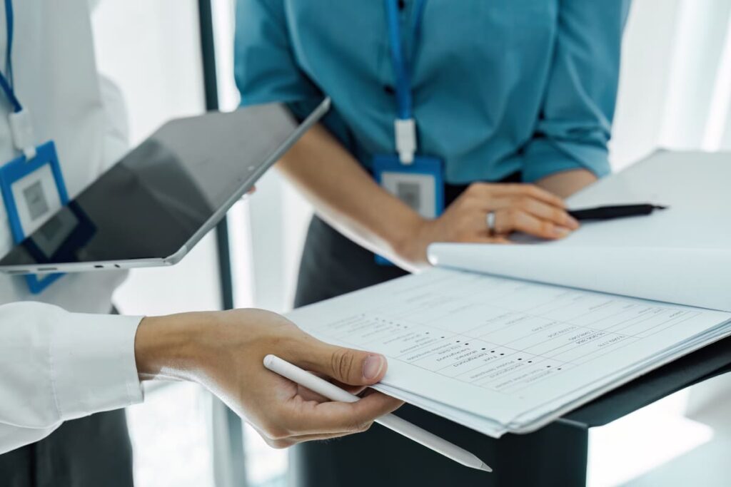 Profesional en recepción hospitalaria gestionando la diversa documentación que trata un auxiliar administrativo en sanidad.