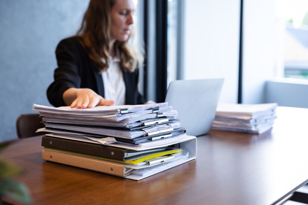 Primer plano de facturas y contratos, ejemplos de documentos que gestiona un auxiliar administrativo.